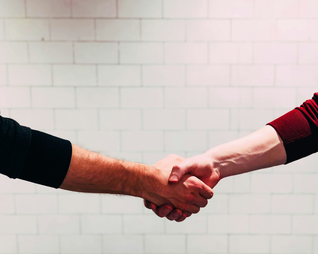 A homeowner and a tradesperson shaking hands after agreeing a job